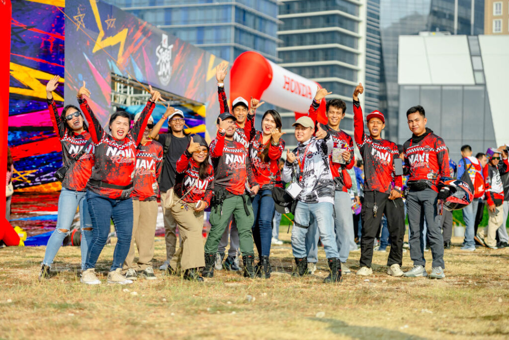 A dynamic group of riders wearing red and black jerseys jumping happily in the air at the Honda Riders Convention Visayas outdoor venue.