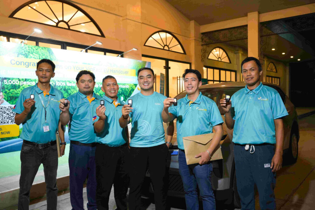 Four men in matching blue shirts proudly display their vehicle keys in a line, smiling for the camera after successfully completing the Green GSM Philippines driver registration process.