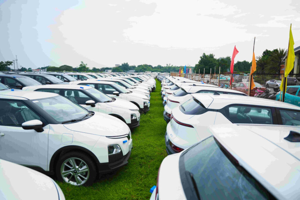 Thousands of white hybrid and electric vehicles are parked in organized rows across a large outdoor lot in preparation for the upcoming Green GSM Philippines driver partner fleet expansion in Metro Manila.