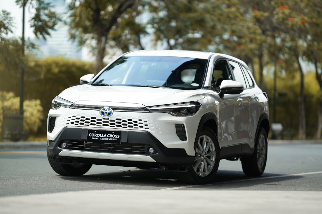 A white Toyota Corolla Cross Hybrid parked on a street, featured in the Toyota promos September 2026.