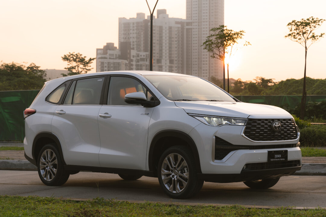 A white Toyota Zenix parked in front of a city skyline at sunset, part of the Toyota promos September 2026.
