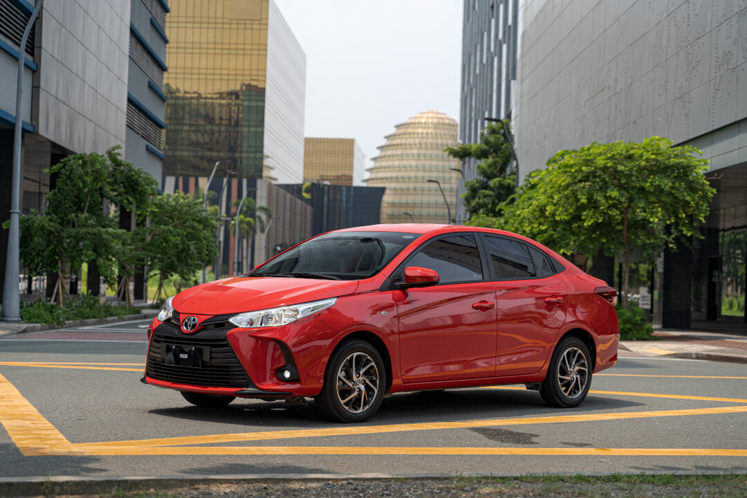 A bright red Toyota Vios sedan driving on a city street, included in the Toyota promos September 2026.