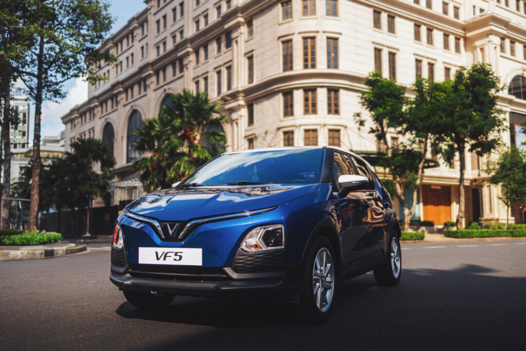 A dynamic, low-angle photograph of a blue VinFast VF5, showcasing its aggressive front fascia and 'V' LED signature lighting, soon to be featured prominently at new VinFast EV showrooms Philippines.