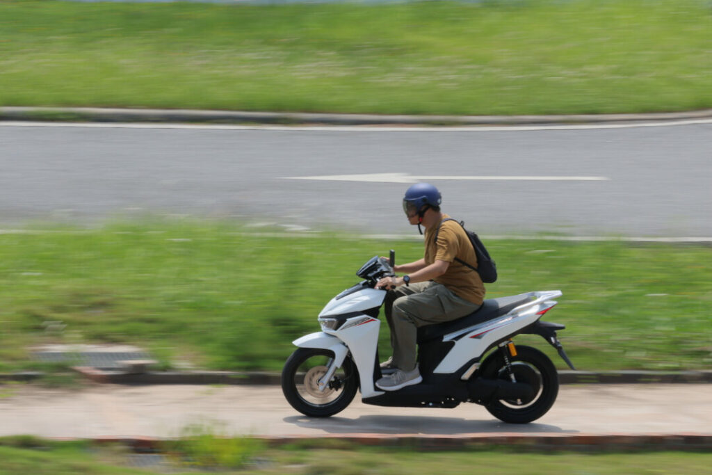 Rider testing white VinFast E-Motorcycles model on paved road during test drive